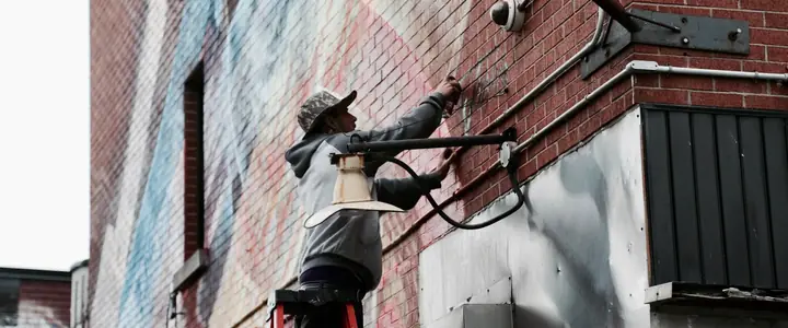 Técnico en una escalera instalando una cámara de seguridad en una fachada